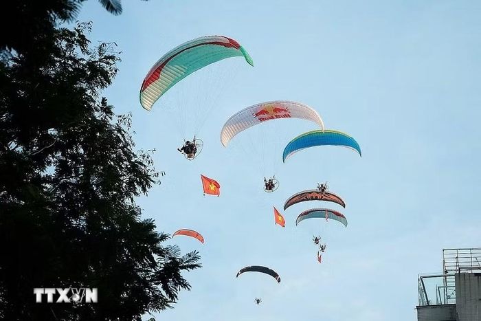 Tiết mục bay dù lượn mang theo cờ Tổ quốc trên bầu trời Hồ Tây, tạo điểm nhấn sinh động trong không gian văn hóa-du lịch của Lễ hội Sen Hà Nội năm 2026. (Ảnh: Phạm Tuấn Anh/TTXVN)