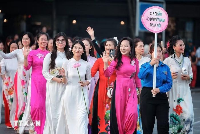Các thành viên Câu lạc bộ Di sản Áo dài Việt Nam thành phố Hà Nội trong trang phục áo dài họa tiết sen tham gia đoàn diễu hành, góp phần tôn vinh vẻ đẹp áo dài Việt Nam. (Ảnh: Phạm Tuấn Anh/TTXVN)