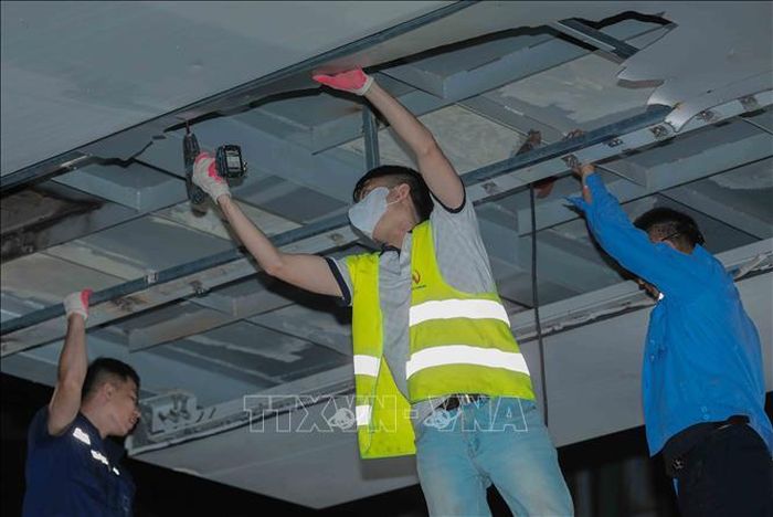 Các công nhân khẩn trương, cẩn thận tháo dỡ những tấm ốp Alu bị vỡ tại khu vực nhà ga Láng trong đêm. Ảnh: Phan Phương/TTXVN