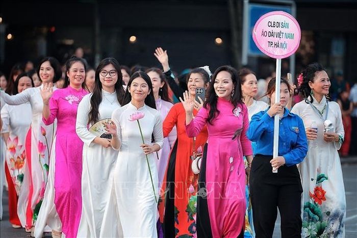 Các thành viên Câu lạc bộ Di sản Áo dài Việt Nam TP. Hà Nội trong trang phục áo dài họa tiết sen tham gia đoàn diễu hành, góp phần tôn vinh vẻ đẹp áo dài Việt Nam. Ảnh: Phạm Tuấn Anh/TTXVN