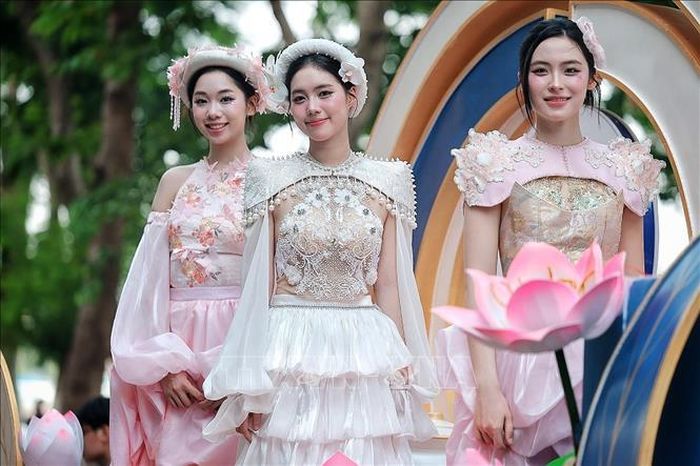 Các người mẫu trong trang phục lấy cảm hứng từ hoa sen trình diễn trên xe hoa. Ảnh: Phạm Tuấn Anh/TTXVN