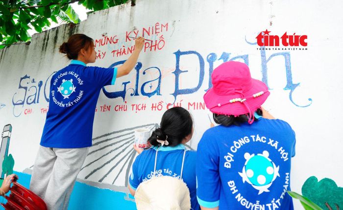 Các sinh viên tình nguyện trường Đại học Nguyễn Tất Thành trang trí, làm mới lại bức tường với chủ đề về những công trình nổi bật chào mừng 50 năm Ngày Thành phố Sài Gòn - Gia Định chính thức vinh dự mang tên Chủ tịch Hồ Chí Minh.