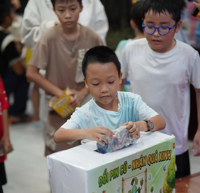 Một em nhỏ mang pin đã qua sử dụng đến đổi quà tại điểm tiếp nhận của chương trình.
