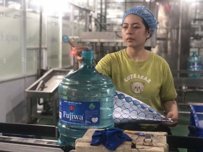 Nữ công nhân Công ty TNHH Fujiwa Việt Nam bên các dây chuyền sản xuất nước khoáng của nhà máy.