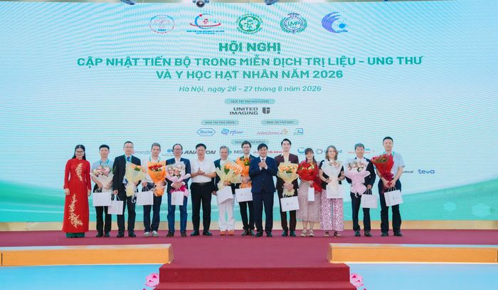 Thứ trưởng Bộ Y tế Đỗ Xuân Tuyên và Giám đốc Bệnh viện Bạch Mai Đào Xuân Cơ tặng hoa các chuyên gia quốc tế.