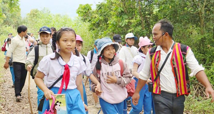  Chàng trai trẻ Đinh Ri (đồng phục Ba Na) hướng dẫn các em nhỏ tham quan du lịch 