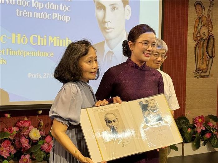Giám đốc Khu Di tích Chủ tịch Hồ Chí Minh tại Phủ Chủ tịch Lê Thị Phượng (áo dài tìm) tiếp nhận những tư liệu, hình ảnh quý về Chủ tịch Hồ Chí Minh do cộng đồng người Việt tại Pháp trao tặng. Ảnh: Hữu Chiến/PV TTXVN tại Pháp