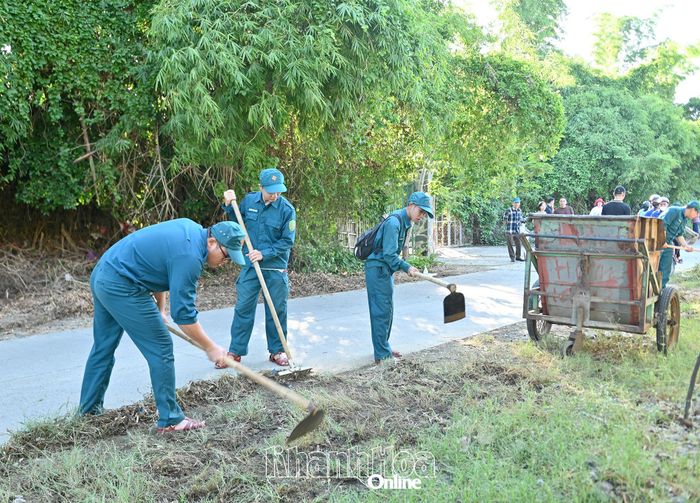 Lực lượng dân quân phát quang bụi rậm, cỏ dại ven đường.