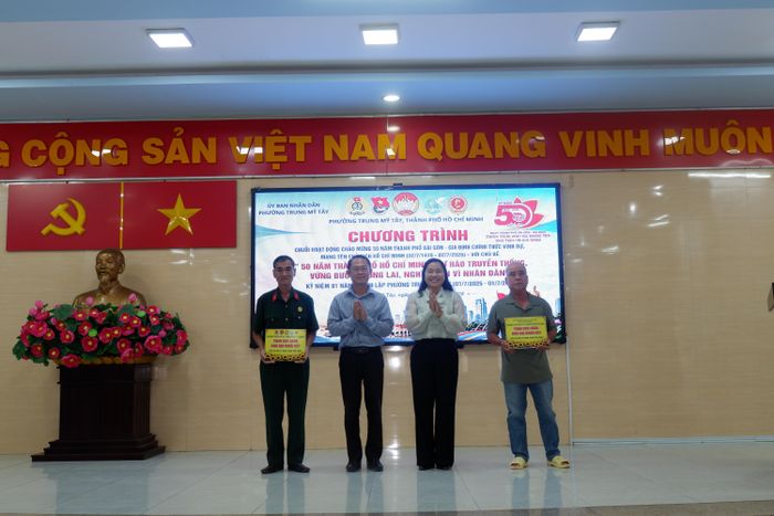  Ông Nguyễn Xuân Hiển, Trưởng phòng Văn hóa - Xã hội phường Trung Mỹ Tây, trao bảng tượng trưng hỗ trợ sửa chữa hai căn nhà cho các hộ dân có hoàn cảnh khó khăn. 