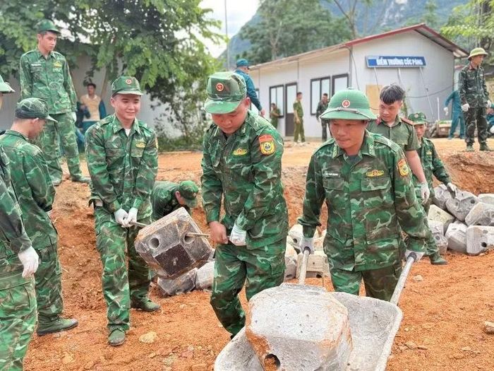 Cán bộ, chiến sĩ phối hợp các lực lượng tham gia vận chuyển vật liệu xây dựng thi công.