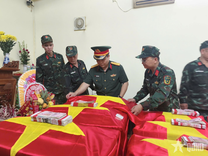 Đại tá Nguyễn Minh Khôi, Phó chính ủy Bộ CHQS tỉnh Tuyên Quang, cùng cán bộ, chiến sĩ Đội tìm kiếm, quy tập hài cốt liệt sĩ thực hiện nghi thức phủ Quốc kỳ lên các hài cốt liệt sĩ tại Nhà quàn Đội tìm kiếm, quy tập hài cốt liệt sĩ, Bộ CHQS tỉnh Tuyên Quang. 