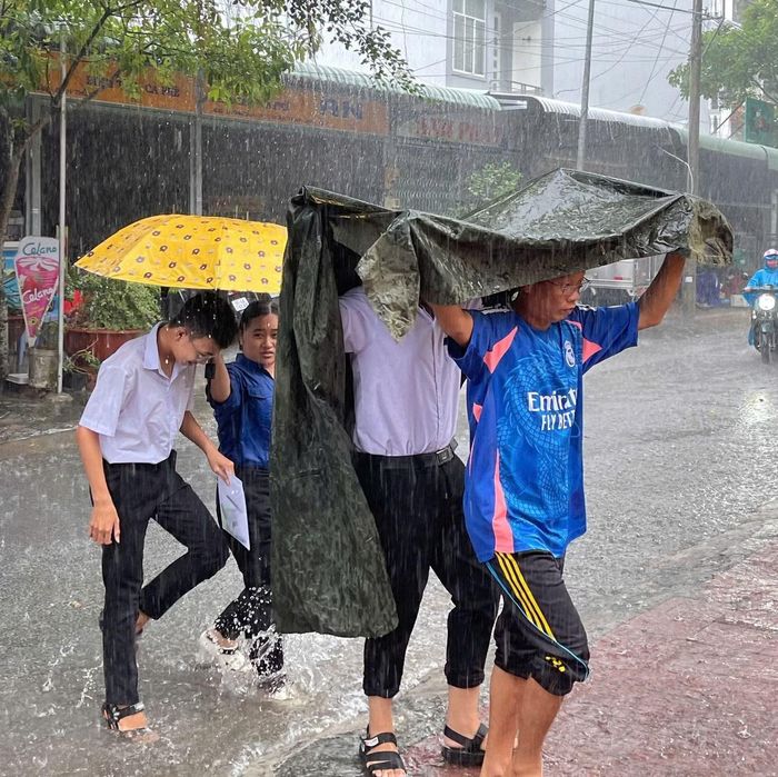 Thanh niên tình nguyện cùng phụ huynh hỗ trợ thí sinh vào phòng thi dưới trời mưa như trút.