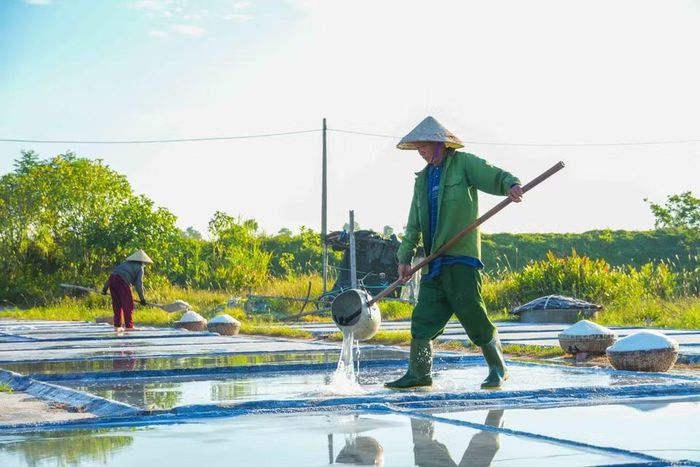Diêm dân đổ nước lên các ô nại để chuẩn bị cho việc thu hoạch muối vào ngày tiếp theo. (Ảnh: Hữu Quyết/TTXVN)