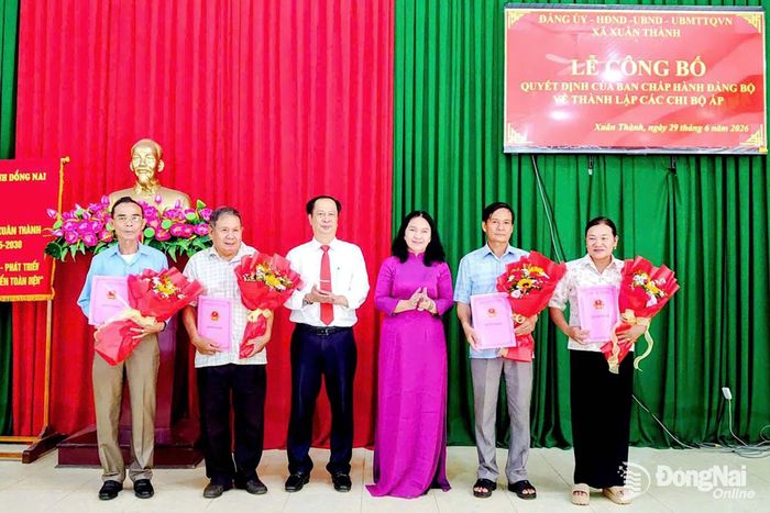 Bí thư Đảng ủy, Chủ tịch HĐND xã Xuân Thành Lâm Hữu Tú và Phó Bí thư Đảng ủy, Chủ tịch UBND xã Xuân Thành Nguyễn Thị Thùy Linh trao quyết định, tặng hoa cho các trưởng ấp sau sắp xếp. Ảnh: ĐPCC