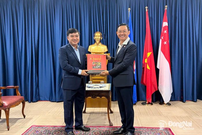Thành ủy viên, Phó Chủ tịch UBND thành phố Đồng Nai Hồ Văn Hà và ông Trần Phước Anh, Đại sứ Việt Nam tại Singapore trao quà tặng và chụp hình lưu niệm.