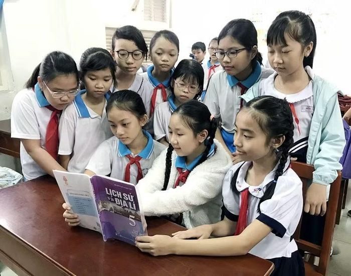 Các học sinh lớp 5 tìm hiểu môn lịch sử qua sách giáo khoa