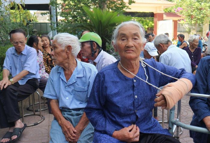 Bà Cao Thị Mai với cánh tay băng bó đi đăng ký lấy mẫu ADN tìm lại em trai.