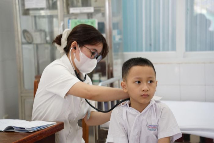 Nhân viên y tế thăm khám sức khỏe cho trẻ em tại trạm y tế. Ảnh: TRÂM ANH