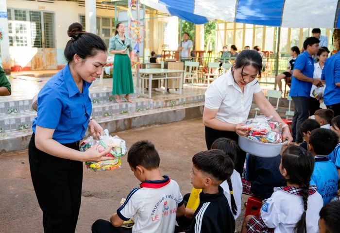 Chị Rơ Châm Byich (bìa trái) tặng quà cho thiếu nhi có hoàn cảnh khó khăn.