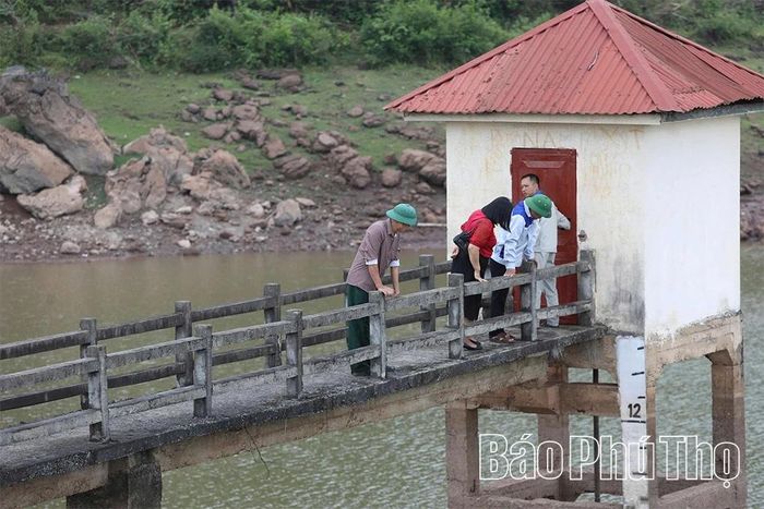 Cán bộ Chi nhánh Thủy lợi khu vực Tân Lạc kiểm tra công trình thủy lợi hồ Bông Canh, xã Tân Lạc.