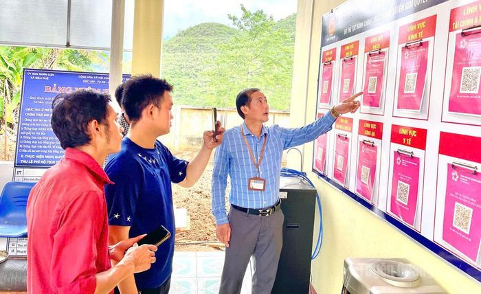 Cán bộ Trung tâm Phục vụ hành chính công xã Mậu Duệ hướng dẫn người dân quét mã QR để tra cứu và thực hiện thủ tục hành chính trực tuyến.