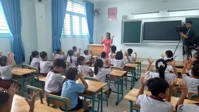 Học sinh tiểu học nghe giáo viên Trường tiểu học Trần Đại Nghĩa giới thiệu về trường.