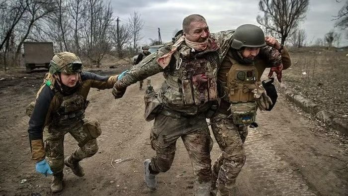 Binh sĩ Ukraine dìu đồng đội bị thương. Ảnh: The New York Times.