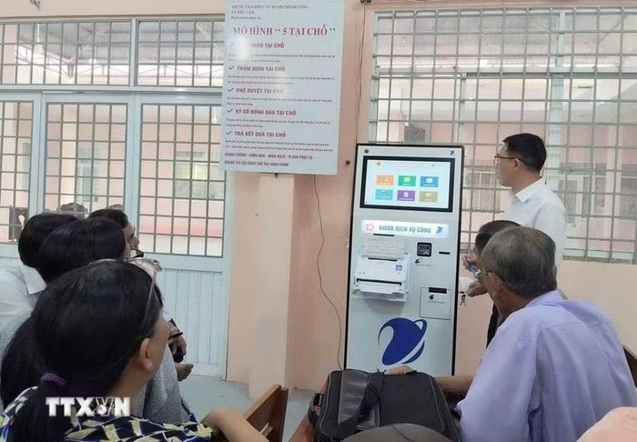 Cán bộ Trung tâm Phục vụ hành chính công xã Phú Lâm (tỉnh An Giang) hướng dẫn người dân các thao tác gửi, kiểm tra hồ sơ thủ tục hành chính bằng kiốt thông minh. (Ảnh: Công Mạo/TTXVN)