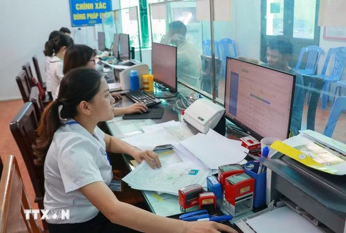 Cán bộ trung tâm phục vụ hành chính công làm thủ tục cho người dân. (Ảnh: Công Luật/TTXVN)