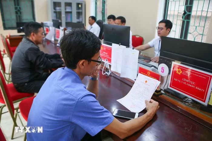 Người dân kiểm tra lại giấy tờ thủ tục tại một trung tâm phục vụ hành chính công. (Ảnh: Công Luật/TTXVN)