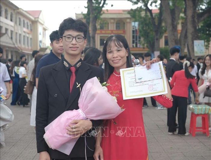 Nguyễn Khắc Công chụp ảnh cùng mẹ trong Lễ tuyên dương học sinh giỏi tại trường. Ảnh: TTXVN phát
