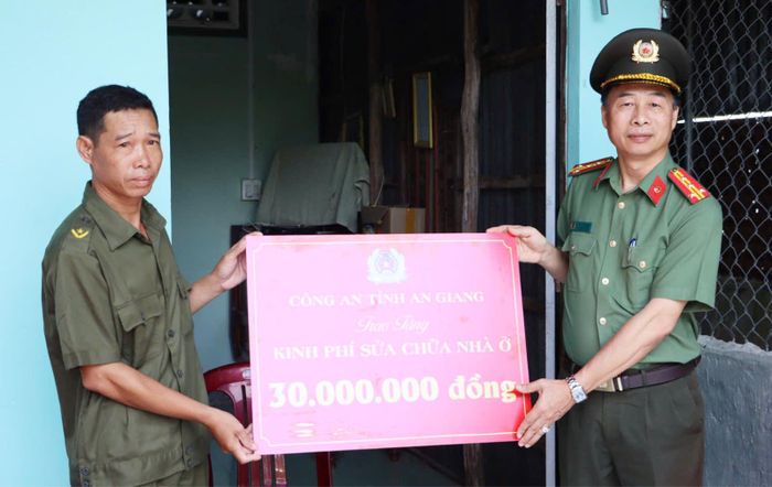 Đại tá Đào Hải Đăng, Phó Giám đốc Công an tỉnh An Giang trao kinh phí hỗ trợ sửa chữa nhà cho gia đình đồng chí Nguyễn Văn Minh.