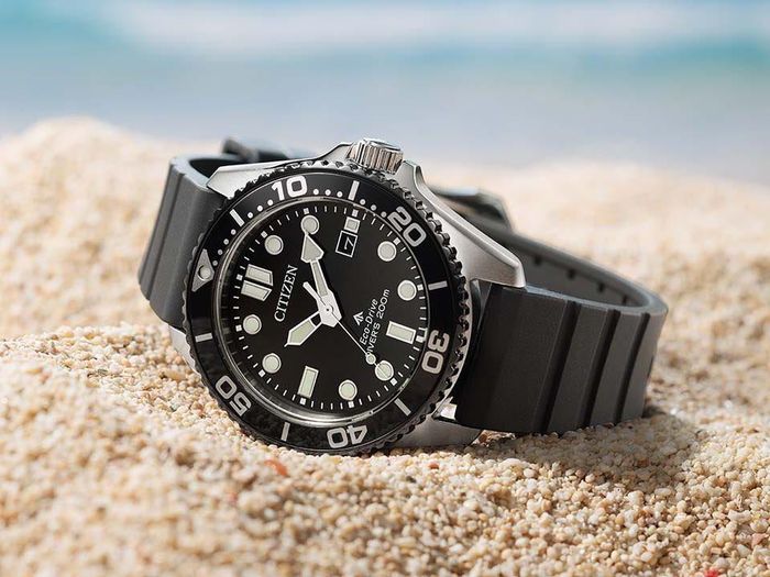 Citizen Promaster Marine BN0266-07E với mặt số đen, vòng bezel đen và dây đeo đen đặt trên cát.