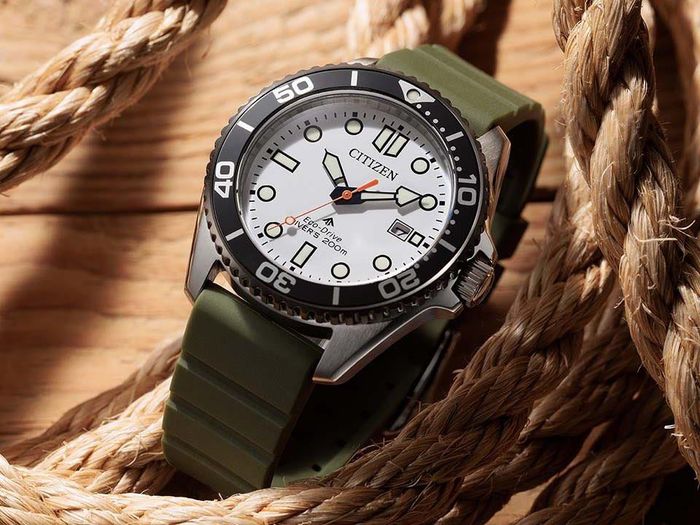 Đồng hồ lặn Citizen Promaster Marine BN0265-00A với mặt số trắng, bezel đen, vỏ thép không gỉ và dây đeo xanh olive đặt trên dây thừng.