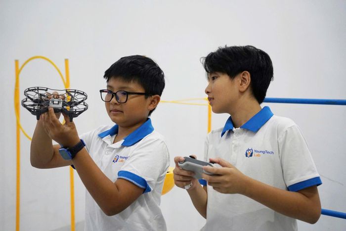 Hồ Nguyễn Thiên Ân (trái) say sưa điều khiển thiết bị vượt chướng ngại vật, một hoạt động giúp em nuôi dưỡng niềm yêu thích lập trình. Ảnh: TRÂM ANH