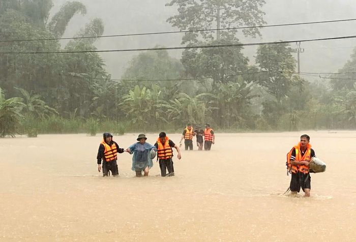 Lực lượng Công an xã Cần Yên đưa, cõng người cao tuổi qua khu vực ngập sâu, đưa đến nơi an toàn.