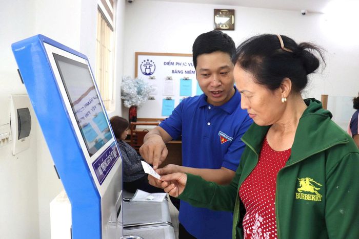 Người dân xã Bát Tràng được lực lượng thanh niên tình nguyện tích cực hướng dẫn thực hiện thủ tục hành chính trực tuyến. Ảnh: Phương Lộc