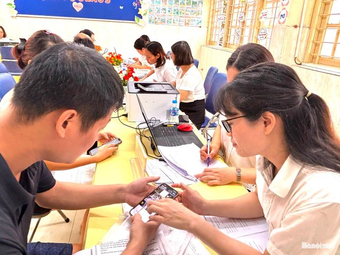 Cán bộ tuyển sinh hỗ trợ phụ huynh đăng ký tuyển sinh trực tuyến. Ảnh: NM