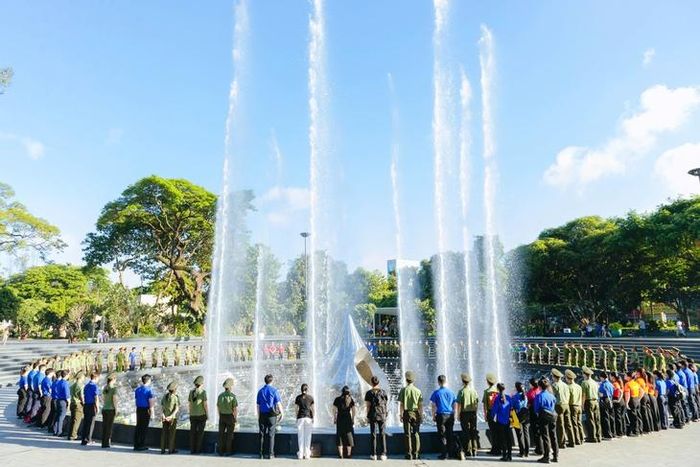 Các đại biểu và đoàn viên thanh niên thực hiện nghi thức dâng hoa tại Tượng đài Giọt nước, Công viên số 1 Lý Thái Tổ. Ảnh: Bích Phương.
