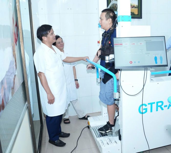 PGS.TS Đào Xuân Cơ, Giám đốc Bệnh viện Bạch Mai; PGS.TS Vũ Văn Giáp - Phó Giám đốc Bệnh viện Bạch Mai trò chuyện cùng bệnh nhân tập luyện với hệ thống robot chỉnh dáng đi (Ảnh: Nguyên Hà)