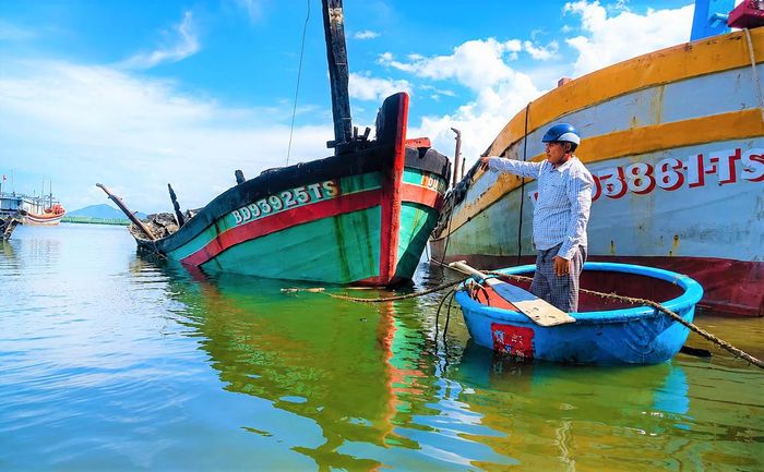 Ngư dân Lê Văn Sang đứng nhìn tàu cá BĐ 93925 TS bị cháy đen trơ khung. Ảnh: ĐS.