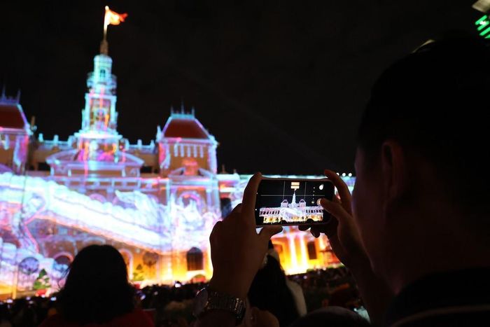 Người dân lưu lại hình ảnh ấn tượng từ những màn trình chiếu 3D mapping. Ảnh: Hồng Đạt - TTXVN