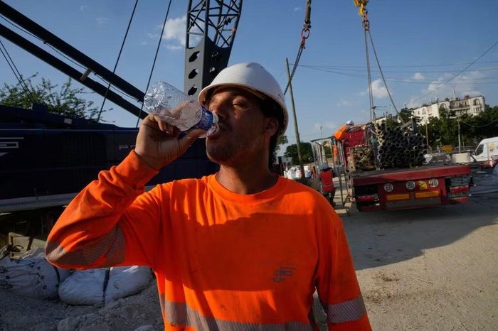 Công nhân xây dựng uống nước tại một công trường ở Paris, Pháp, ngày 24/6/2026. Ảnh: AP/Michel Euler.