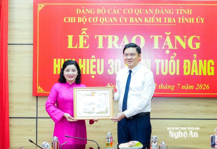 Phó Bí thư Thường trực Tỉnh ủy, Chủ tịch HĐND tỉnh Hoàng Nghĩa Hiếu trao Huy hiệu 30 năm tuổi Đảng cho đồng chí Nguyễn Thị Hồng Hoa - Ủy viên Ban Thường vụ, Chủ nhiệm Ủy ban Kiểm tra Tỉnh ủy. Ảnh: Phạm Bằng