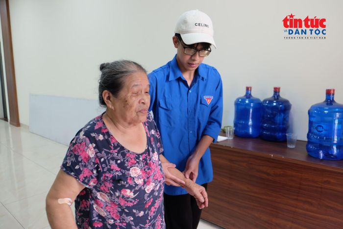 Một tình nguyện viên ân cần dìu cụ bà cao tuổi vào khu vực thu nhận mẫu sinh phẩm.