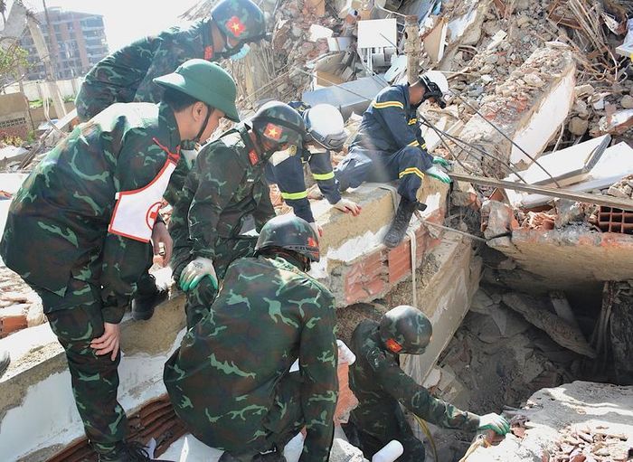 Lực lượng Quân đội và Công an phối hợp tìm kiếm nạn nhân bị kẹt bên trong đống đổ nát. Ảnh: Hoàng Vũ