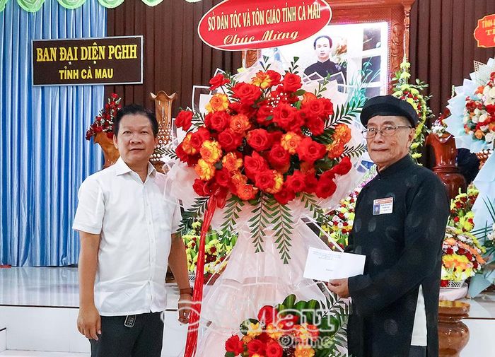 Ông Nguyễn Văn Đảm, Phó Giám đốc Sở Dân tộc và Tôn giáo tỉnh Cà Mau, trao hoa và quà chúc mừng Ban Đại diện Phật giáo Hòa Hảo tỉnh.