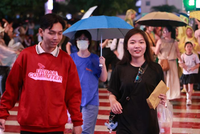 Du khách đội mưa đến trung tâm thành phố chờ đón xem trình diễn nghệ thuật