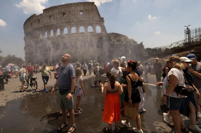 Du khách giải nhiệt bằng hệ thống phun sương nước gần đấu trường La Mã, Rome, Italy, ngày 26/6. (Ảnh: Reuters)