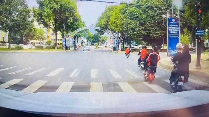 Camera hành trình một xe ô-tô ghi lại cảnh nhóm học sinh điều khiển xe đạp điện không đội mũ bảo hiểm và vượt đèn đỏ gây mất an toàn giao thông giữa trung tâm phường Buôn Ma Thuột.